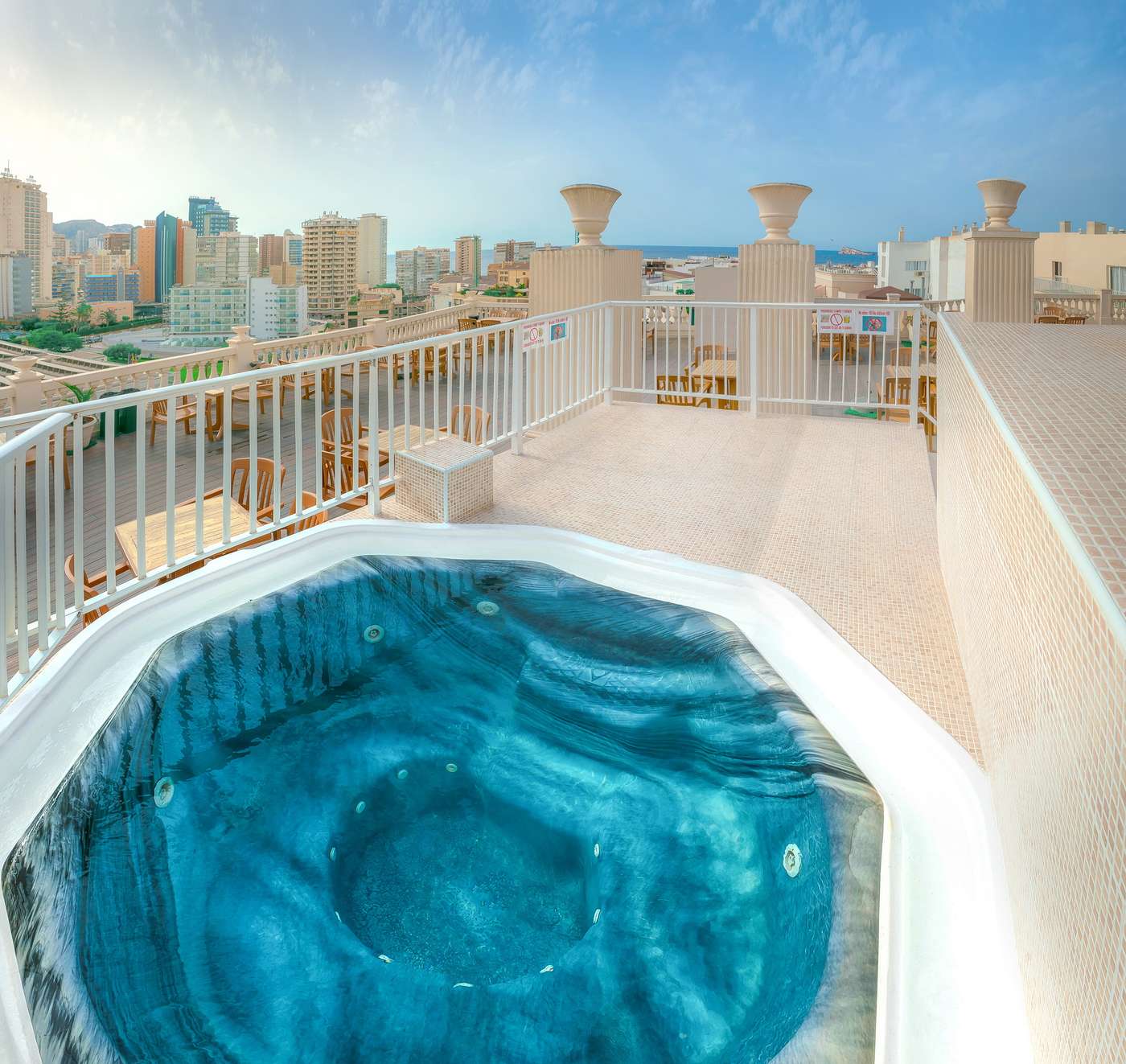 Jacuzzi on rooftop terrace, on a higher level than the seating area for the bar, with tables and chairs.
