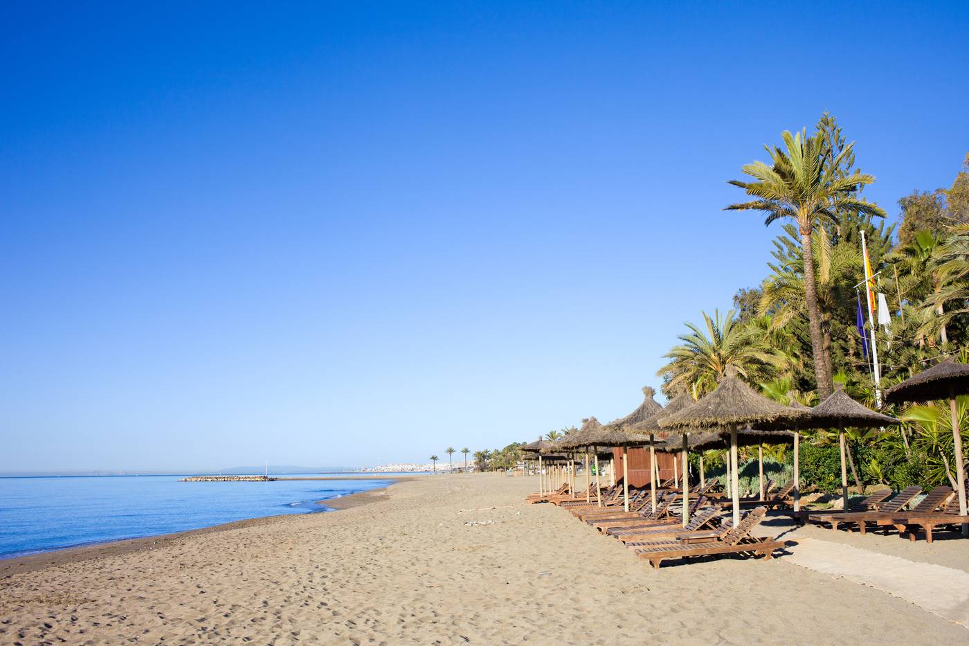 Sun loungers on a sandy beach by the Mediterranean Sea at the popular resort of Marbella in southern Spain, Costa del Sol, Andalusia region, Malaga province.