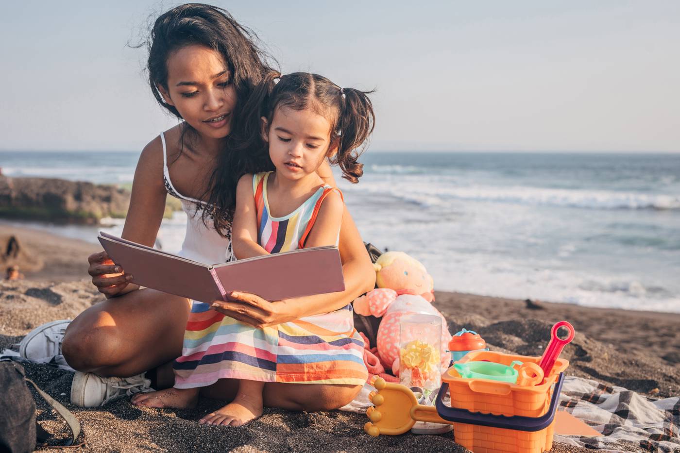 Mother and daughter reading on beach
