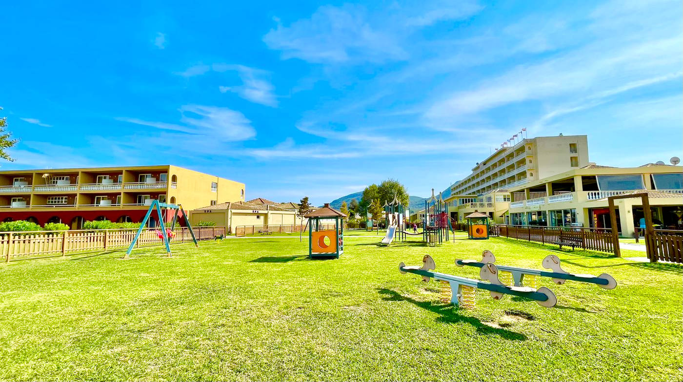 Exterior overview shot  of hotel with grassy areas and swingset