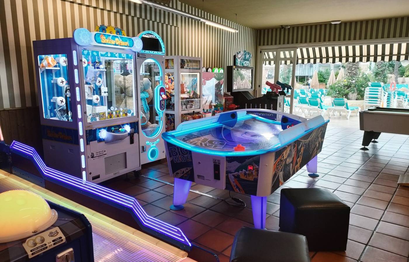 Arcade with air hockey table and other lit up arcade games around.