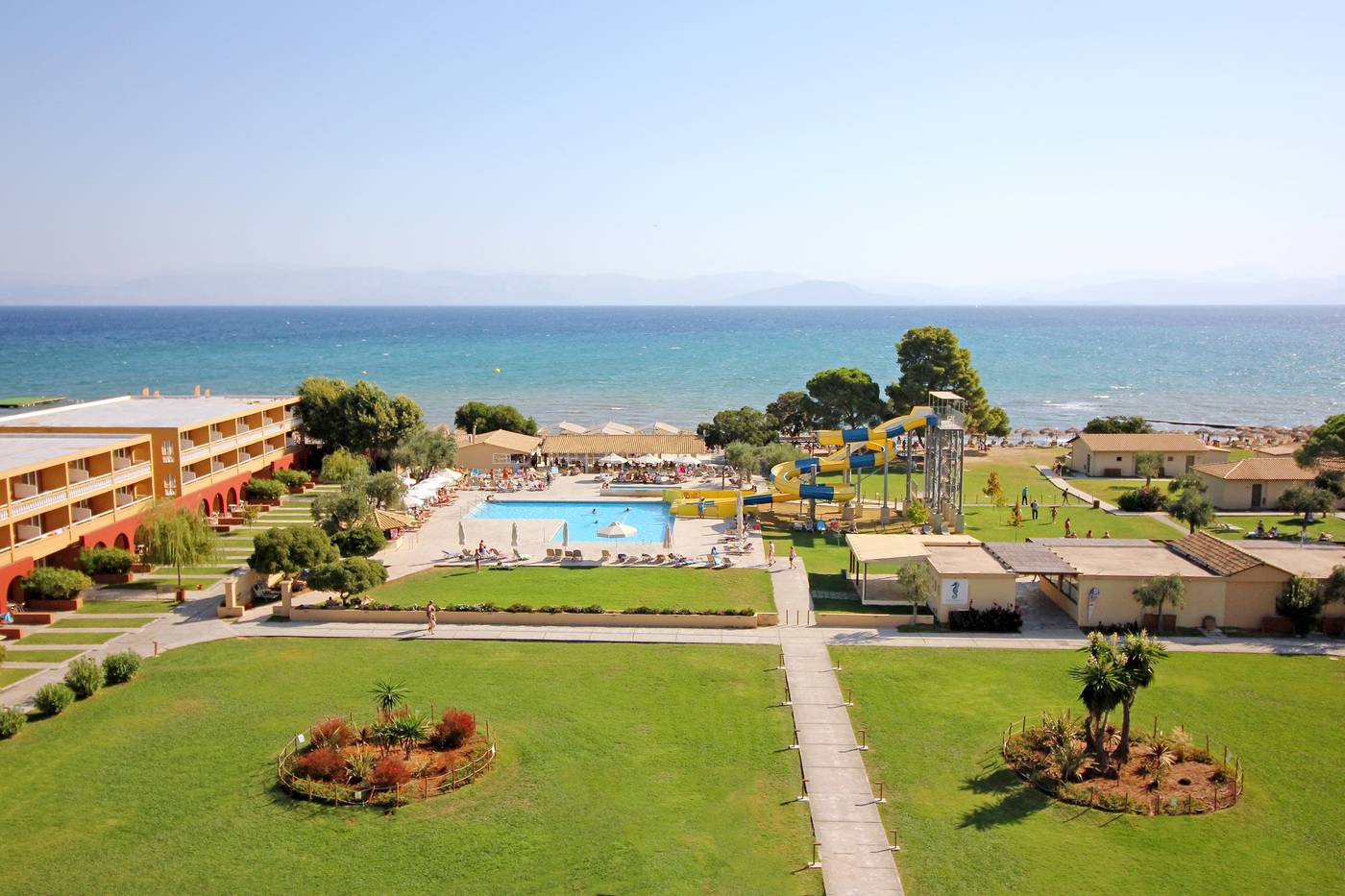 Hotel pool area and grass areas and sea view in background